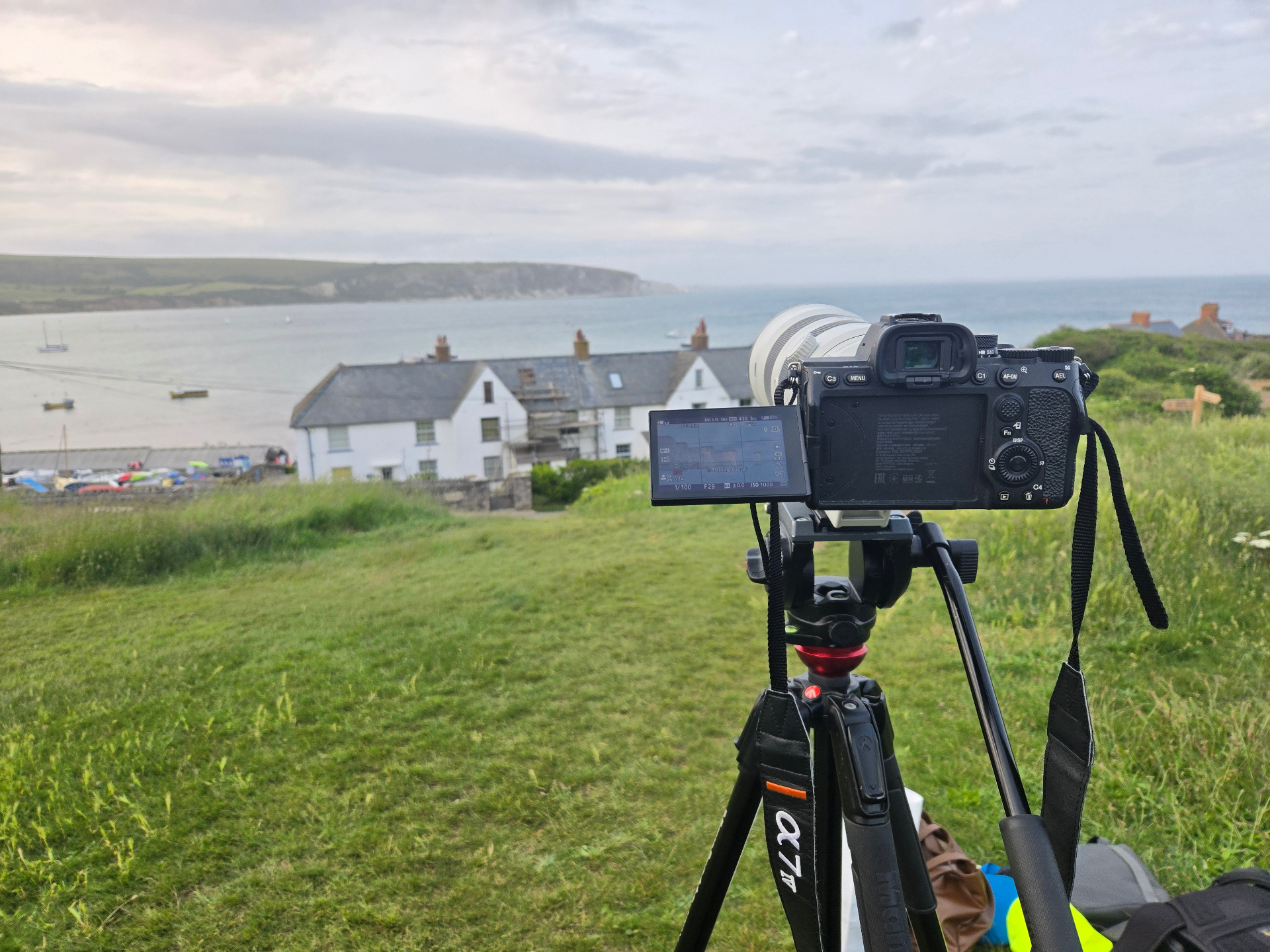 Cinema camera on a tripod overlooking a UK coastal village at dusk